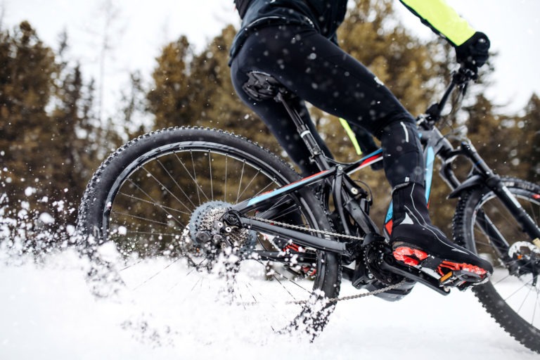 Midsection of mountain biker riding in snow outdoors in winter